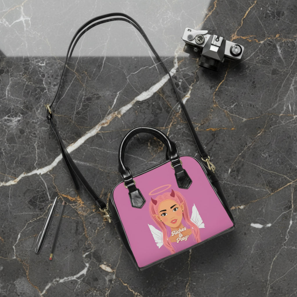 Pink handbag with a devilish angel character design on marble contertop