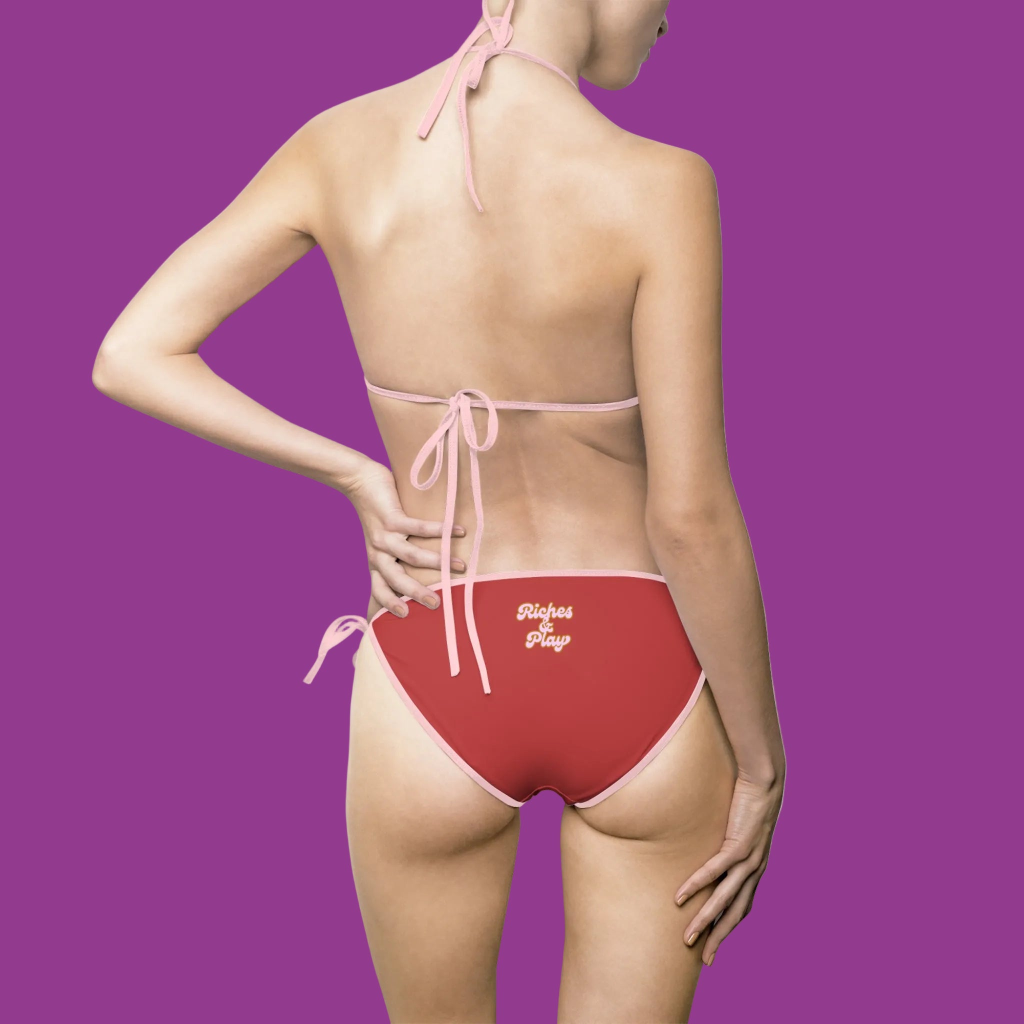 Red bikini bottom with 'Riches & Play' text on a purple background