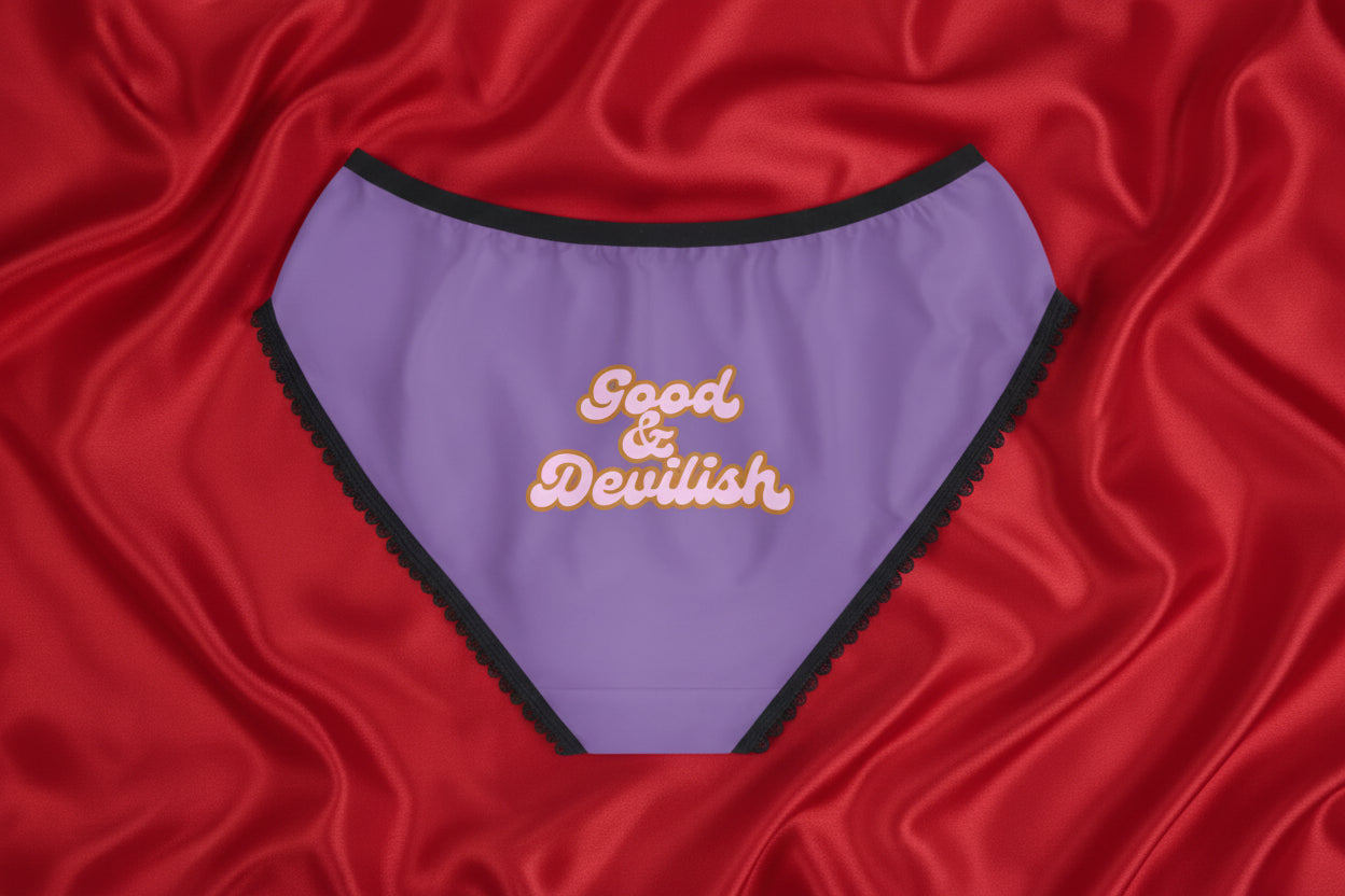 Purple underwear with 'Good & Devilish' text on a red ilk comforter