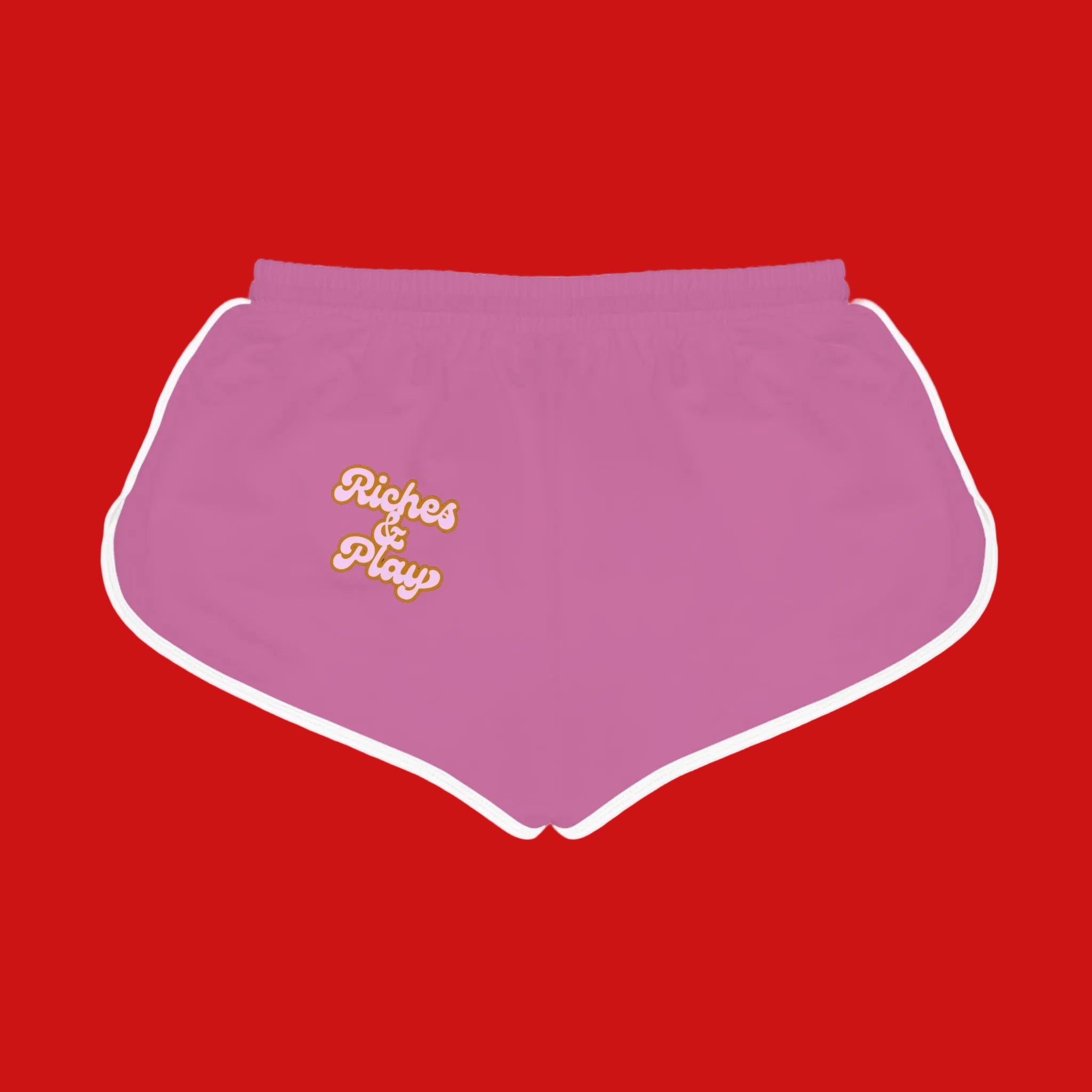 Pink doggy shorts with 'Riches & Play' text on a red background